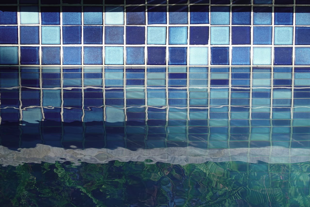 Close-up view of blue and turquoise tiles reflecting in a calm swimming pool.